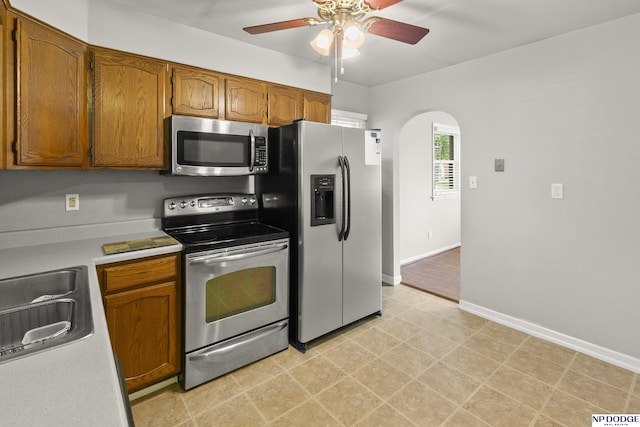 402 W 30th Ave, Bellevue, NE 68005 - kitchen featuring appliances with stainless steel finishes, arched walkways, ceiling fan, light countertops, and brown cabinetry