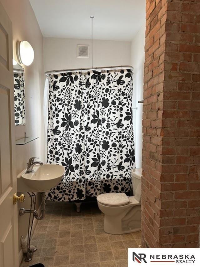 3123 R St, Lincoln, NE 68503 - bathroom featuring brick wall and curtained shower