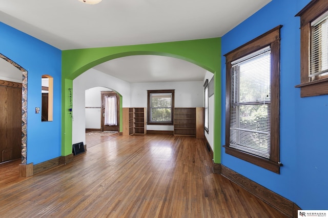 2615 C St, Lincoln, NE 68502 - unfurnished living room with wood finished floors, plenty of natural light, and arched walkways