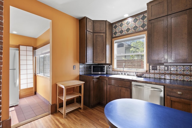 2615 C St, Lincoln, NE 68502 - kitchen featuring stainless steel appliances, dark countertops, decorative backsplash, and dark brown cabinetry