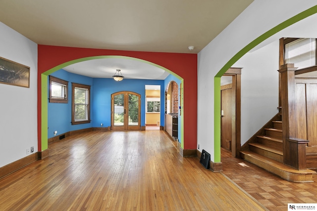 2615 C St, Lincoln, NE 68502 - spare room featuring arched walkways, wood finished floors, and stairs