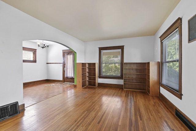 2615 C St, Lincoln, NE 68502 - unfurnished living room with hardwood / wood-style floors, a chandelier, and arched walkways