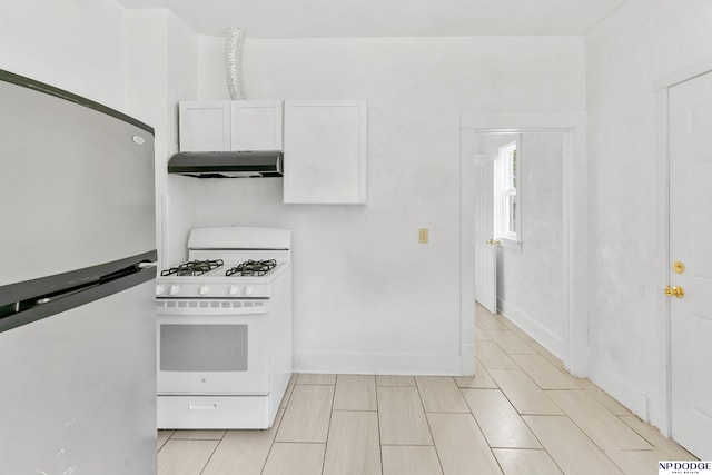2738 Browne St, Omaha, NE 68111 - kitchen with freestanding refrigerator, white gas range, under cabinet range hood, and white cabinets