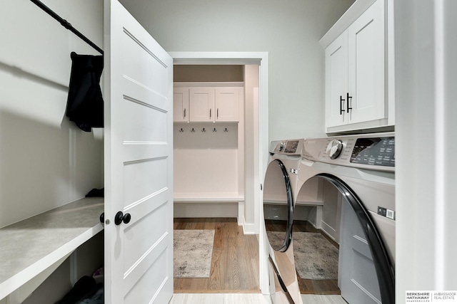20709 Woodridge Dr, Gretna, NE 68028 - washroom featuring independent washer and dryer, light wood finished floors, and cabinet space