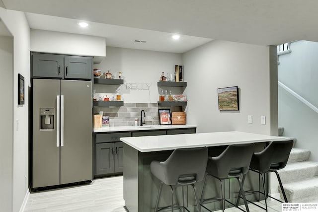 20709 Woodridge Dr, Gretna, NE 68028 - kitchen featuring stainless steel refrigerator with ice dispenser, open shelves, a kitchen bar, light countertops, and a peninsula