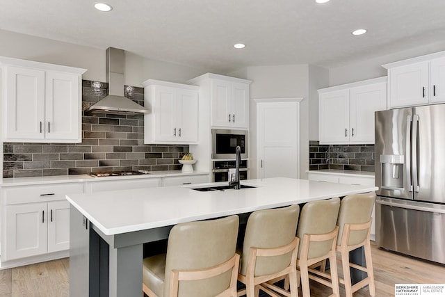 20709 Woodridge Dr, Gretna, NE 68028 - kitchen with appliances with stainless steel finishes, wall chimney exhaust hood, a kitchen island with sink, light countertops, and recessed lighting