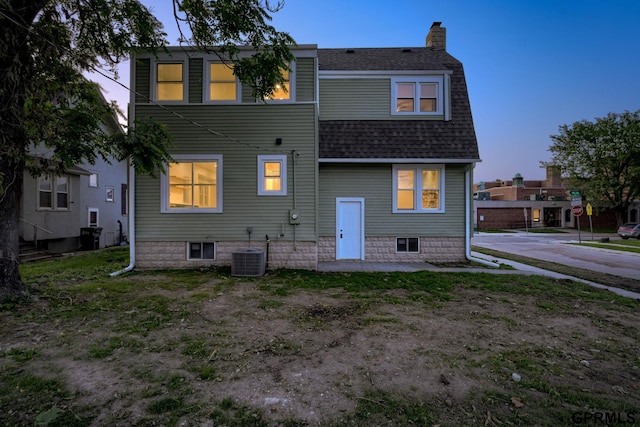 2551 Meredith Ave, Omaha, NE 68111 - back of house at dusk featuring a shingled roof and a chimney