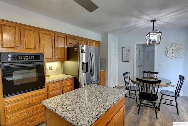 4625 S 222nd St, Elkhorn, NE 68022 - kitchen with black oven, stainless steel refrigerator with ice dispenser, brown cabinets, wood finished floors, and a chandelier