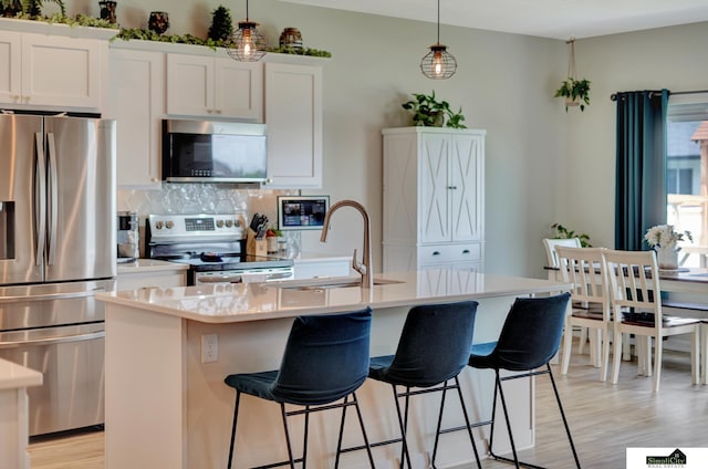 7420 Isidore Dr, Lincoln, NE 68516 - kitchen with stainless steel appliances, backsplash, a center island with sink, light wood finished floors, and light countertops