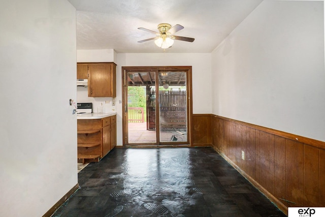 813 Janes View St, Papillion, NE 68046 - kitchen featuring wooden walls, a wainscoted wall, ceiling fan, brown cabinetry, and under cabinet range hood
