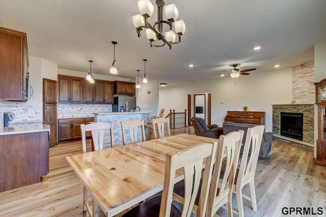 3320 Fairway Dr, Plattsmouth, NE 68048 - dining area featuring light wood-style flooring, a ceiling fan, a chandelier, a fireplace, and recessed lighting