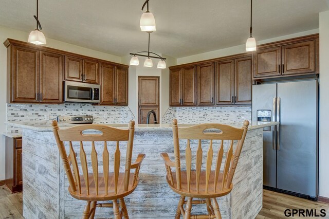 3320 Fairway Dr, Plattsmouth, NE 68048 - kitchen with stainless steel appliances, light wood-style floors, tasteful backsplash, and hanging light fixtures