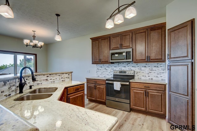 3320 Fairway Dr, Plattsmouth, NE 68048 - kitchen featuring stainless steel appliances, light wood finished floors, tasteful backsplash, decorative light fixtures, and a chandelier