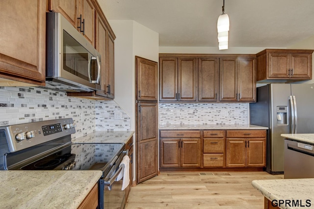 3320 Fairway Dr, Plattsmouth, NE 68048 - kitchen featuring appliances with stainless steel finishes, light wood-type flooring, hanging light fixtures, backsplash, and brown cabinetry