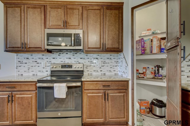 3320 Fairway Dr, Plattsmouth, NE 68048 - kitchen featuring stainless steel appliances, backsplash, brown cabinets, and light stone counters