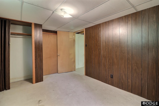 414 N Myers St, Fremont, NE 68025 - unfurnished bedroom with wood walls, unfinished concrete flooring, a closet, and a drop ceiling