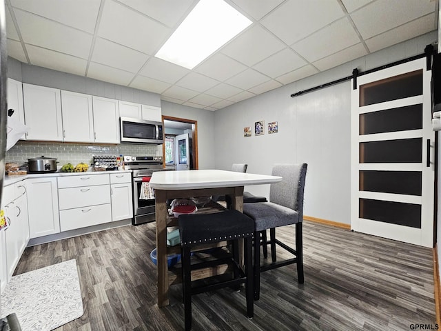 401 Chestnut Ave, Saronville, NE 68975 - kitchen with appliances with stainless steel finishes, a barn door, dark wood-type flooring, white cabinets, and a drop ceiling