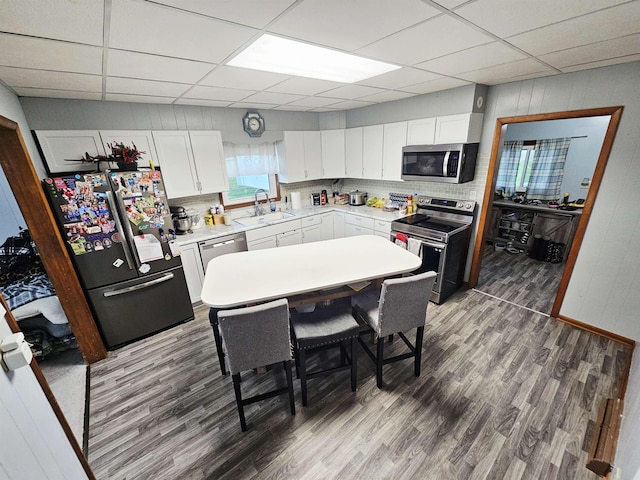 401 Chestnut Ave, Saronville, NE 68975 - kitchen featuring stainless steel appliances, wood finished floors, a drop ceiling, white cabinetry, and light countertops