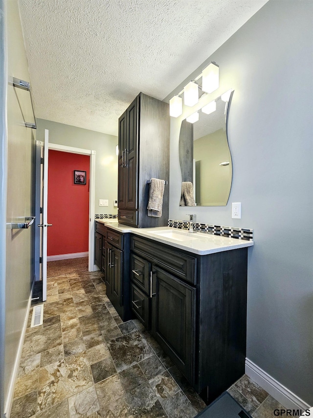 108 W Ridge St, Sutton, NE 68979 - bathroom featuring double vanity, stone finish floors, and a textured ceiling