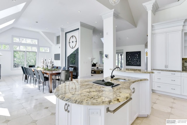 14341 Hamilton St, Omaha, NE 68154 - kitchen featuring ornate columns, light stone counters, white cabinetry, a skylight, and high vaulted ceiling