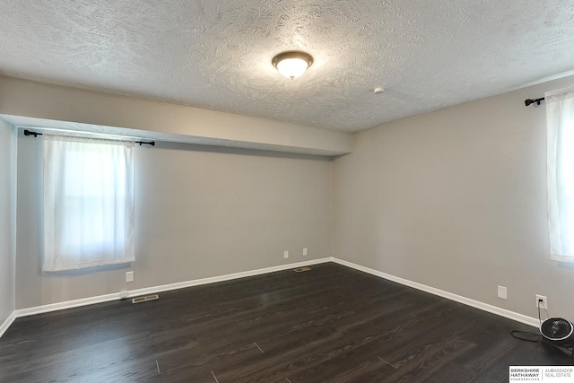 5023 N 96th St, Omaha, NE 68134 - empty room featuring dark wood-type flooring, a textured ceiling, and healthy amount of natural light
