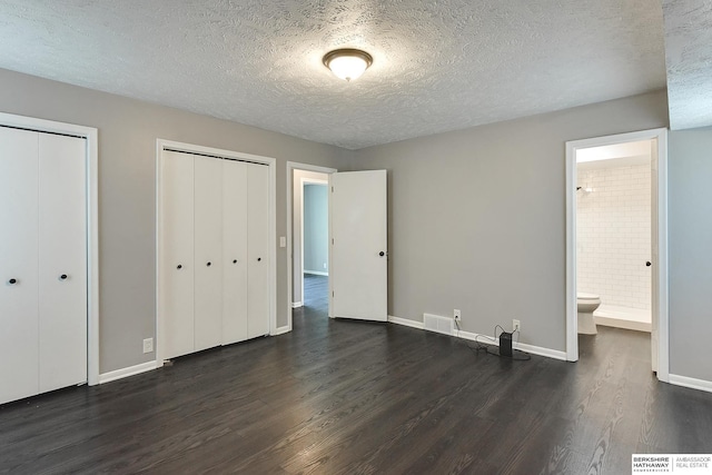 5023 N 96th St, Omaha, NE 68134 - unfurnished bedroom with two closets, dark wood-style floors, a textured ceiling, and ensuite bath