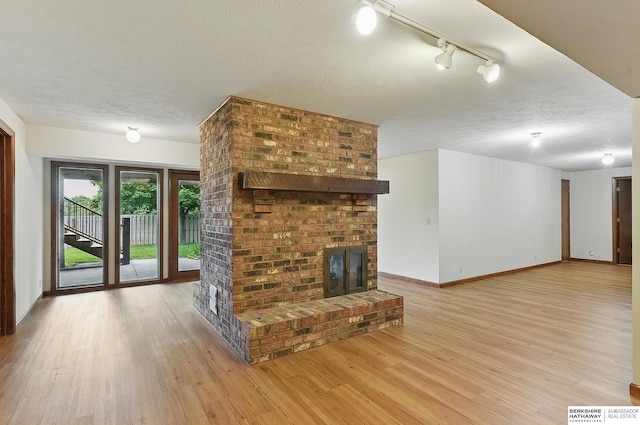 15618 L St, Omaha, NE 68135 - unfurnished living room with a textured ceiling, light wood-style flooring, track lighting, and a fireplace