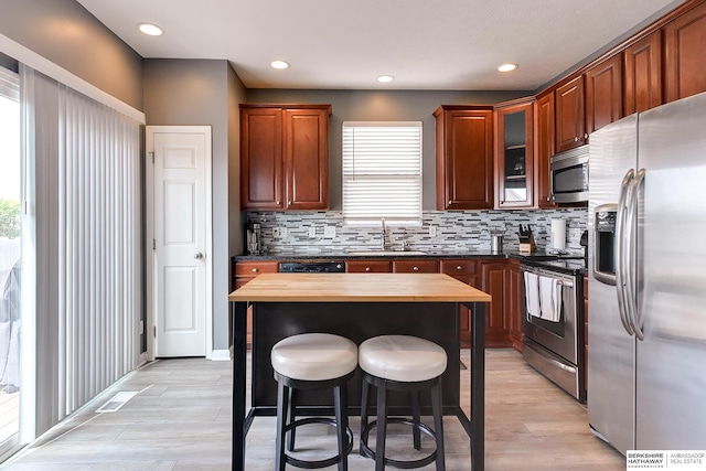 16501 Aurora St, Omaha, NE 68136 - kitchen featuring stainless steel appliances, wooden counters, a kitchen breakfast bar, backsplash, and light wood-style floors