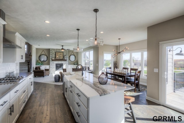 3103 N 184th St, Elkhorn, NE 68022 - kitchen featuring stainless steel gas cooktop, a breakfast bar, a stone fireplace, wall chimney exhaust hood, and open floor plan