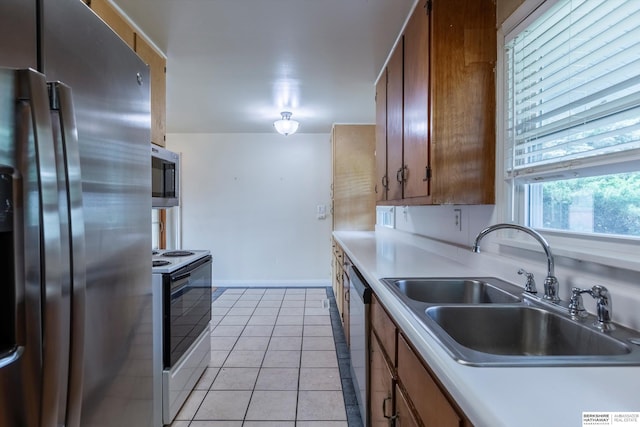 1805 Collins Dr, Bellevue, NE 68005 - kitchen featuring appliances with stainless steel finishes, light tile patterned floors, brown cabinets, and light countertops