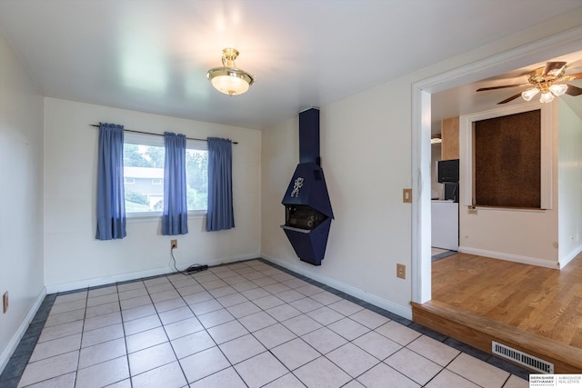 1805 Collins Dr, Bellevue, NE 68005 - unfurnished room with a wood stove, a ceiling fan, and light tile patterned floors