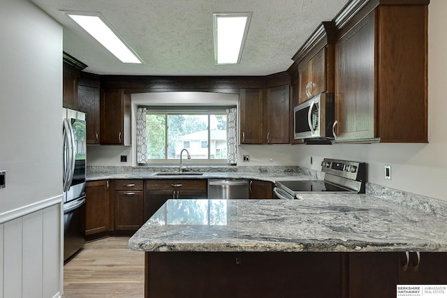 1324 S 162nd St, Omaha, NE 68130 - kitchen with stainless steel appliances, a peninsula, light stone counters, light wood finished floors, and dark brown cabinets