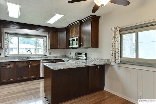 1324 S 162nd St, Omaha, NE 68130 - kitchen featuring appliances with stainless steel finishes, light wood-style floors, a peninsula, dark brown cabinets, and a wainscoted wall