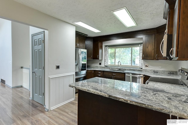 1324 S 162nd St, Omaha, NE 68130 - kitchen with appliances with stainless steel finishes, light wood finished floors, dark brown cabinets, light stone counters, and a textured ceiling
