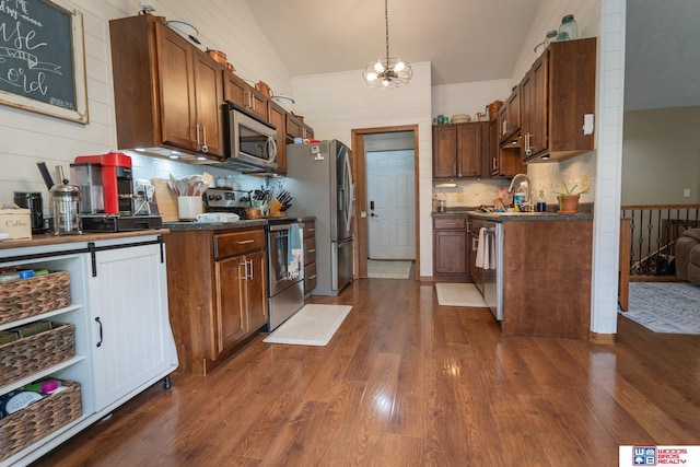 85 Vince Dr, Bennet, NE 68317 - kitchen featuring appliances with stainless steel finishes, dark countertops, dark wood-type flooring, backsplash, and lofted ceiling