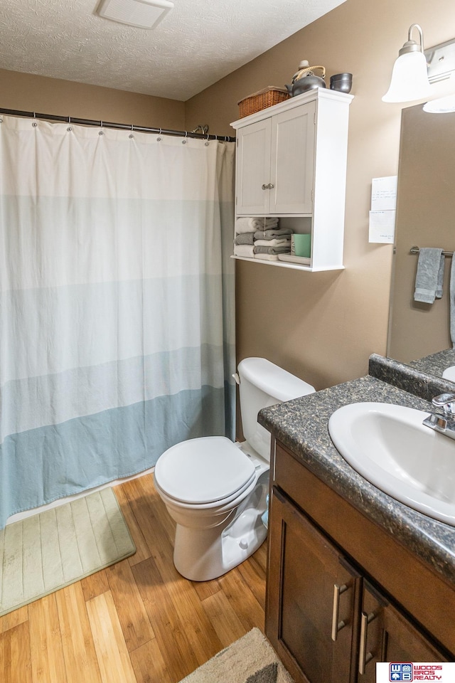 85 Vince Dr, Bennet, NE 68317 - bathroom featuring vanity, wood finished floors, a textured ceiling, and a shower with shower curtain