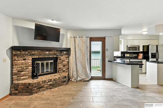 2108 S 62nd St, Omaha, NE 68106 - kitchen with appliances with stainless steel finishes, dark countertops, white cabinets, a brick fireplace, and a peninsula