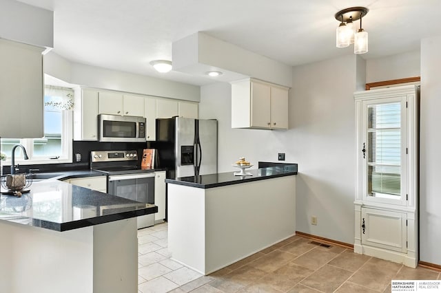 2108 S 62nd St, Omaha, NE 68106 - kitchen featuring appliances with stainless steel finishes, a peninsula, dark countertops, and light tile patterned floors