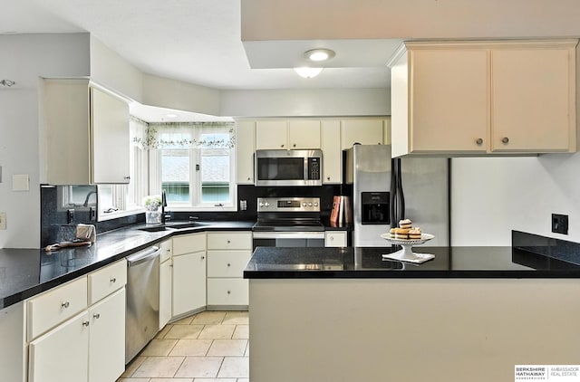 2108 S 62nd St, Omaha, NE 68106 - kitchen with stainless steel appliances, a peninsula, dark countertops, and tasteful backsplash
