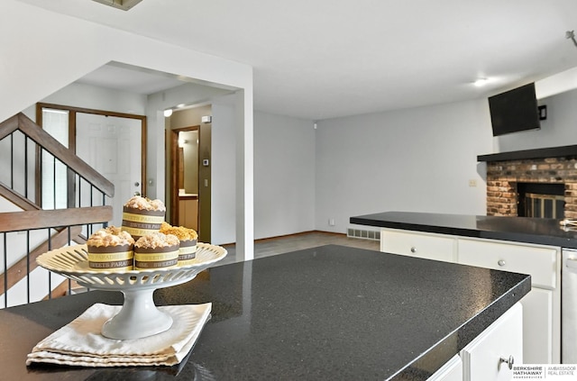 2108 S 62nd St, Omaha, NE 68106 - kitchen with white cabinets, dark countertops, a brick fireplace, and dishwashing machine