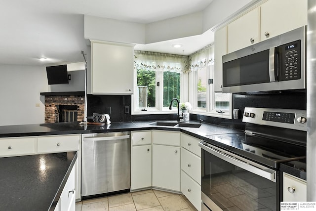 2108 S 62nd St, Omaha, NE 68106 - kitchen featuring stainless steel appliances, dark countertops, a brick fireplace, backsplash, and a peninsula