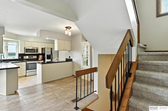 2108 S 62nd St, Omaha, NE 68106 - kitchen featuring stainless steel appliances, dark countertops, a peninsula, and white cabinetry