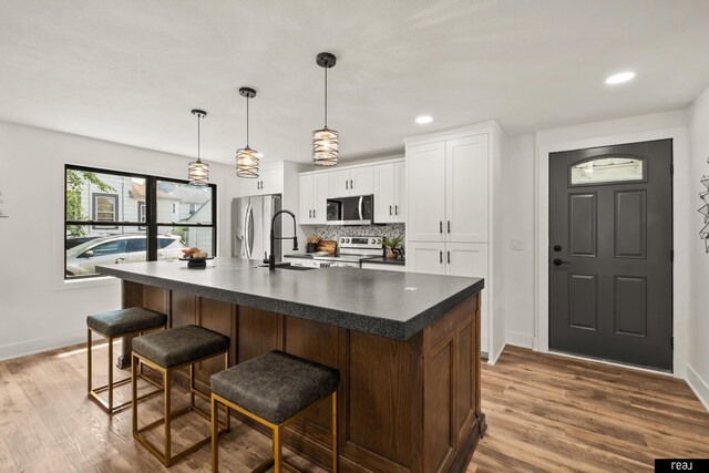316 N 13th St, Tekamah, NE 68061 - kitchen featuring appliances with stainless steel finishes, dark countertops, a kitchen bar, backsplash, and white cabinets