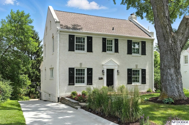 2525 N 55th St, Omaha, NE 68104 - colonial-style house featuring a chimney, brick siding, a shingled roof, and concrete driveway