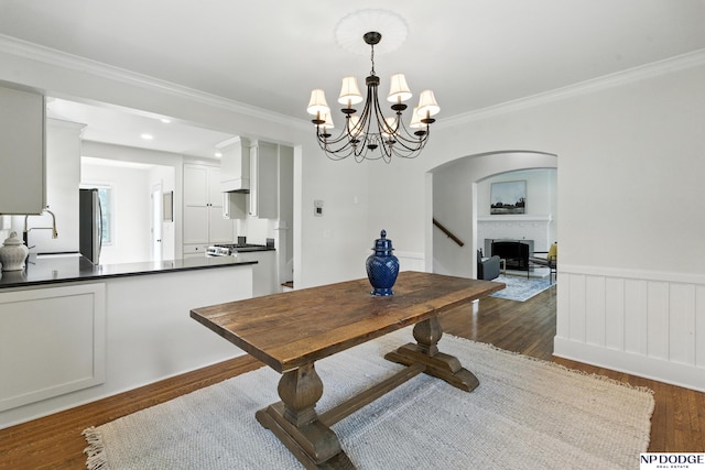 2525 N 55th St, Omaha, NE 68104 - dining room featuring dark wood-type flooring, a brick fireplace, ornamental molding, a chandelier, and arched walkways