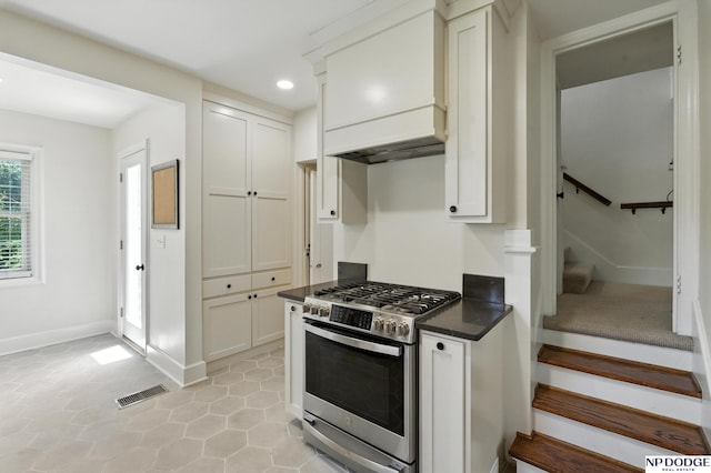2525 N 55th St, Omaha, NE 68104 - kitchen with stainless steel range with gas stovetop, dark countertops, recessed lighting, light tile patterned floors, and white cabinets