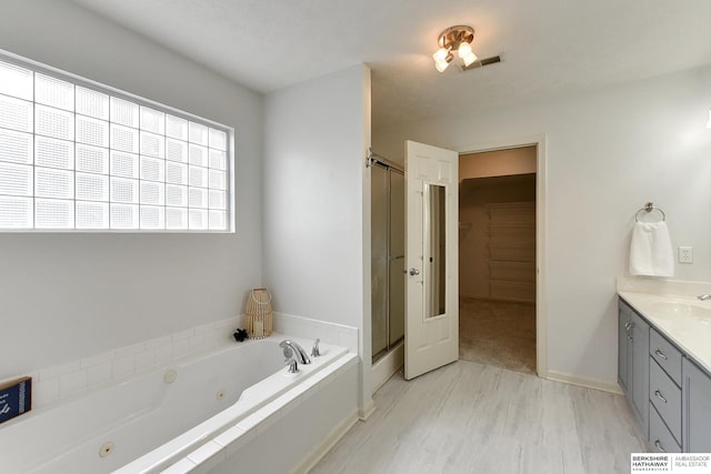 1622 S 179th St, Omaha, NE 68130 - bathroom featuring a tub with jets, vanity, a stall shower, a walk in closet, and wood finished floors