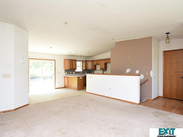 9105 Olive Creek Rd, Hickman, NE 68372 - kitchen with brown cabinets, a peninsula, tasteful backsplash, light carpet, and open floor plan