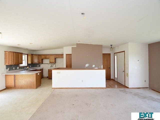 9105 Olive Creek Rd, Hickman, NE 68372 - kitchen with a peninsula, brown cabinetry, lofted ceiling, fridge, and light colored carpet