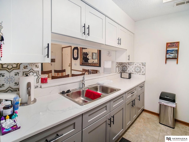 2425 Folkways Blvd Unit 211, Lincoln, NE 68521 - kitchen featuring decorative backsplash, light countertops, gray cabinets, white cabinetry, and a textured ceiling